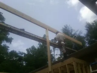 Carpenter setting a ridge beam over a new addition frame — Ice Dam Removal by Roofing Brothers in Massena